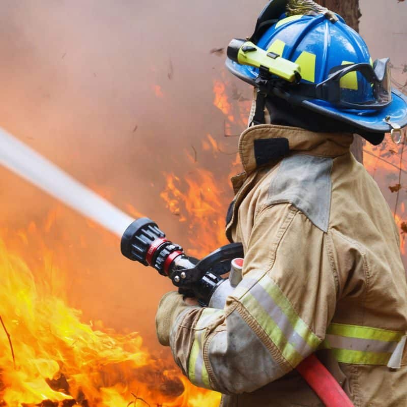 Firefighter battling a blaze with a water hose