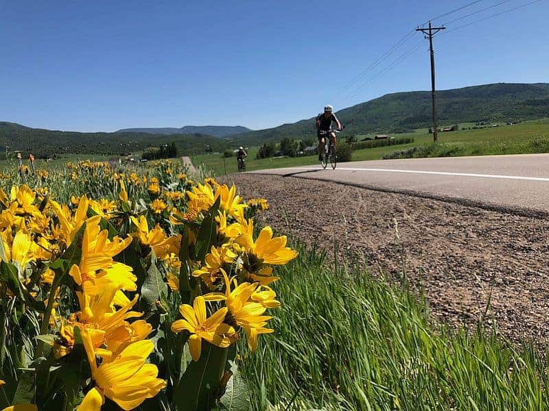 biking on a Colorado road with the mountains in the background